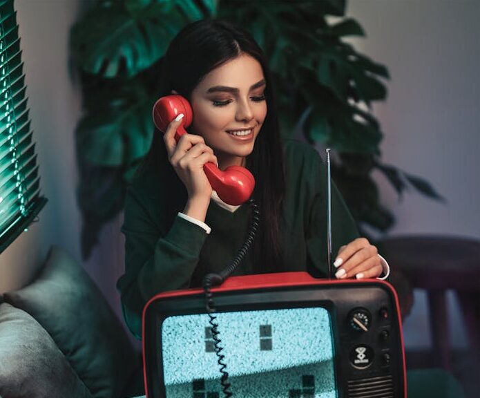 Photo of Woman Sitting on Sofa Holding Red Telephone